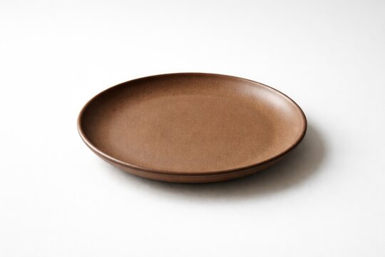 Unadorned brown plate photographed on white studio background