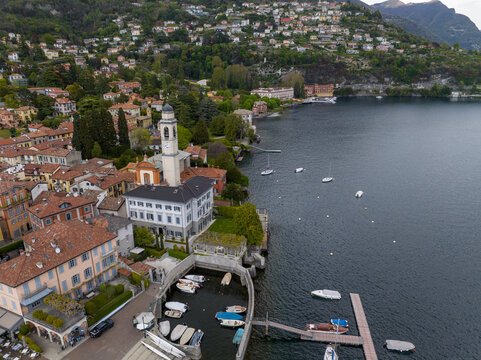 Aerial view of the waterfront featuring the Church of San Vincenzo bell tower, colorful lakeside buildings, and the historic Villa d'Este complex on Lake Como Cernobbio, Lombardia, Italy.