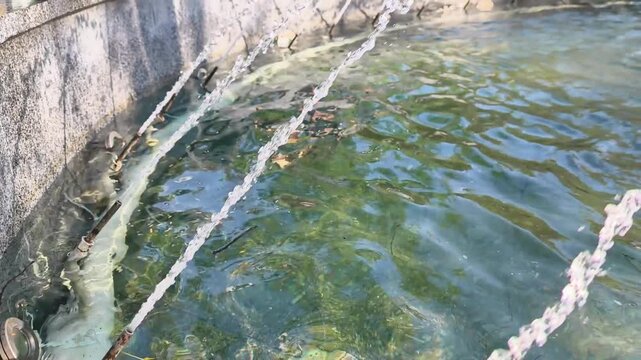 Water Circulation System In Fountain Pool With Pipes And Jets. Water circulation and filtration system in decorative pool with greenish water and ripples.