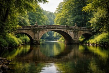 Fototapeta premium Classic stone bridge crossing a calm river surrounded by greenery
