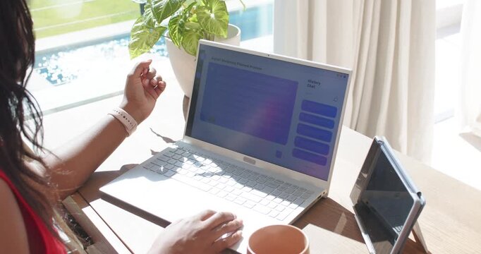 African American woman sitting at home adjusting laptop screen for sun glare near pool, copy space