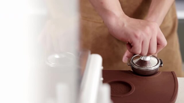 Professional barista prepare espresso coffee use hand-held tamper, tamping freshly ground coffee beans powder in a portafilter in cafe restaurant business shop, coffeemaker preparation brewing process