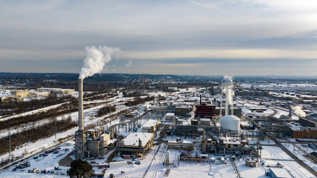 Aerial view of the GE Aerospace industrial complex with smoking chimneys and snow-covered rooftops in Reading, Ohio, United States.