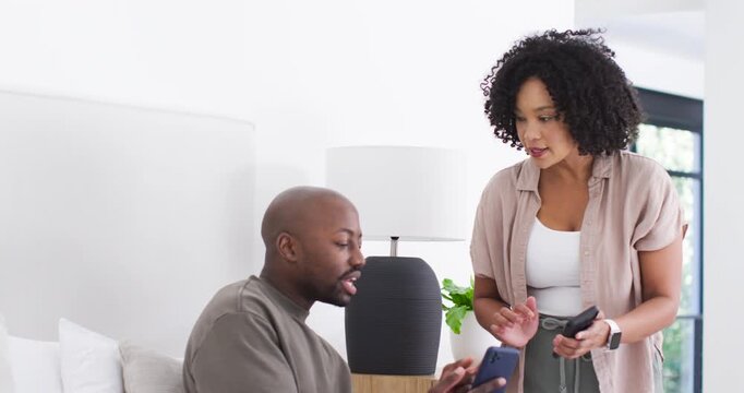 African American couple on couch comparing phones, woman leaning in showing screen, man listening