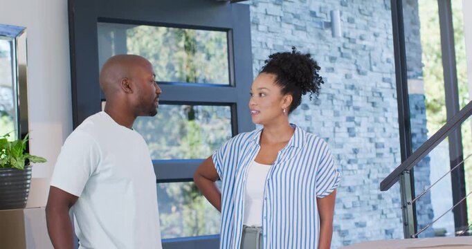 African American couple standing in foyer, man producing red key fob announcing home woman gasping
