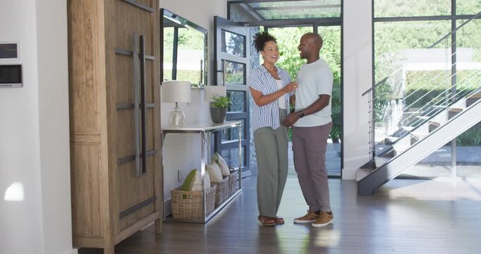 African American couple entering through glass door into foyer, greeting, man lifting woman