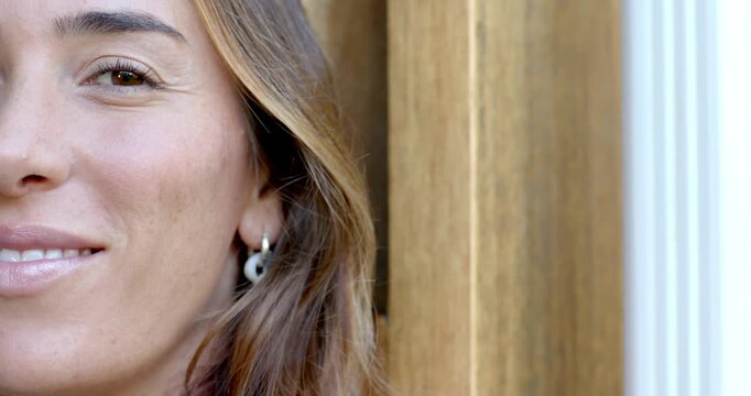 Adult woman reacting to off-camera cue shifting to broad grin at doorframe hoop earring, copy space