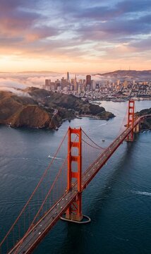 Aeriall vertical view of the Golden Gate Bridge and San Francisco skyline during a dramatic sunset with low fog.