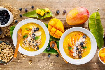 Obraz premium mango smoothie bowls with granola and blueberries for healthy breakfast