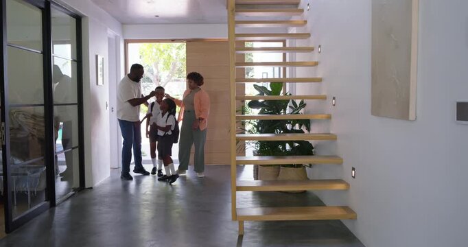 African American family entering front door into kitchen after school, placing backpacks on counter