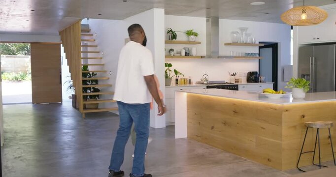 African American couple playfully dancing after man walking toward woman, spinning near wood island
