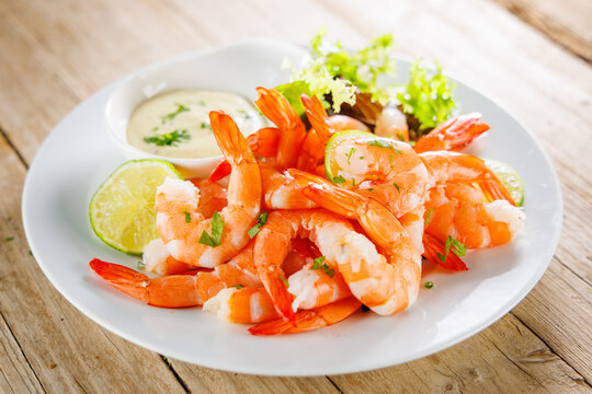 fresh cooked prawns with lime and dipping sauce on a white plate