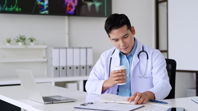 Professional doctor holding a hot coffee drink cup.doing paperwork checking medical documents at workplace. Concentrated physician reading medic form analyzing patient diagnosis or report in hospital.