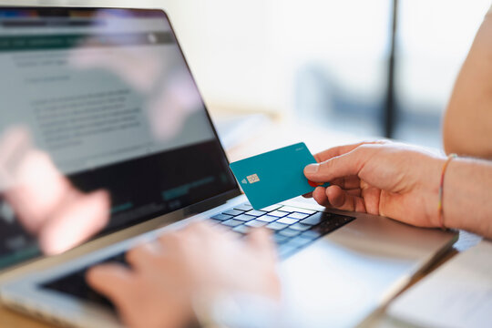 A person uses a credit card to make an online purchase on a laptop.