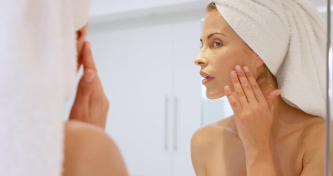 Bathroom, woman and skincare with mirror in home for self care, inspection and clear skin. Happy person, facial and reflection in house with towel for hygiene, grooming and wellness with dermatology