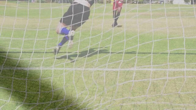 Male attacker striking soccer penalty to score, keeper diving attempting save, path tracing ball