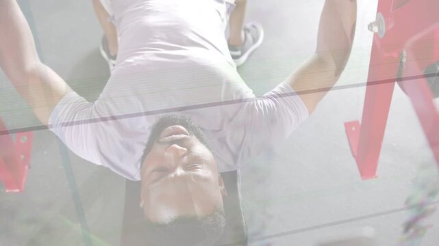 Man gripping handles, starting set on gym bench, pressing for strength with lens flare across frame