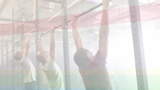 Gym trio reaching for bar, doing aligned pull-ups for power, color band crossing over subjects