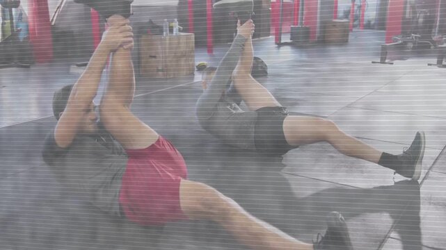 Fitness partners on mats doing hamstring stretch for warmup moving into crunches after trainer cue