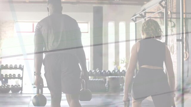 Training partners starting on cue and walking toward windowed wall holding kettlebells for strength