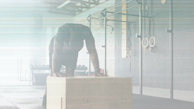 Man bracing plyo box, shifting weight, stepping up, driving upward for fitness amid lens flare