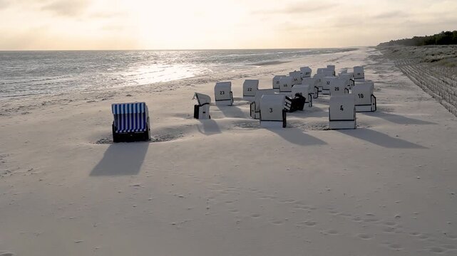 Empty beach chairs are bathed in the light of the rising sun on the beach at the Baltic resort of Prerow on the Darss (Vorpommern Bodden Landscape National Park).