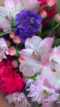 Vertical pull back from pink alstroemeria and purple statice revealing whole mixed flower bouquet with carnations and berries. Floral video for social media content.