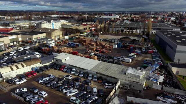 Warehouses, workshops, and parking lots in dense industrial and commercial area in suburbs, France. Aerial forward