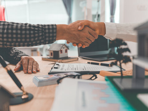 The client and agent shake hands after successfully completing the real estate purchase agreement, demonstrating the handshake between the sales agent and the buyer.