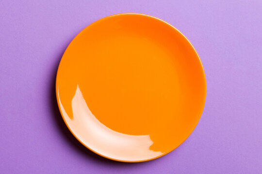 Top view of isolated of colored background empty round orange plate for food. Empty dish with space for your design