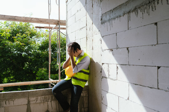Stressed construction worker leaning against a wall at a building site, representing workplace fatigue, emotional pressure, and challenges in the construction industry.