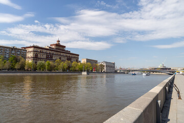 Naklejka premium Scenic view of city river embankment with historic architecture and bridge in distance