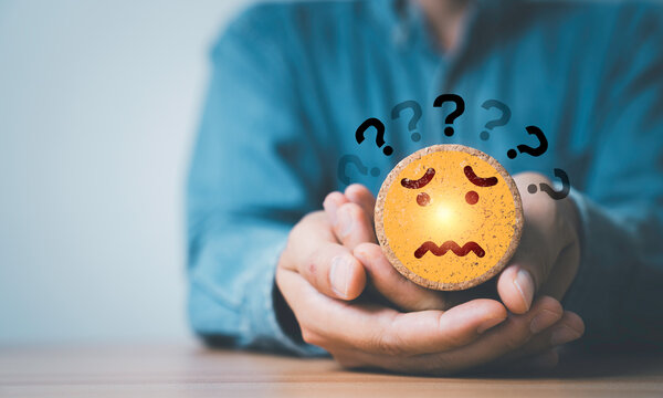 Anxious customer emotion and uncertainty concept with worried emoji face and question marks in hands, representing stress, confusion, mental pressure, difficult decisions, risk and emotional problems