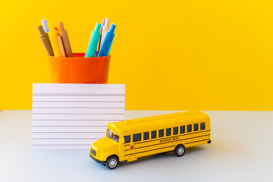 Bright minimal still life featuring toy school bus, blank lined card colorful pens in cup, capturing back to school core trend, dopamine classroom energy, teacher aesthetic playful micro learning vibe