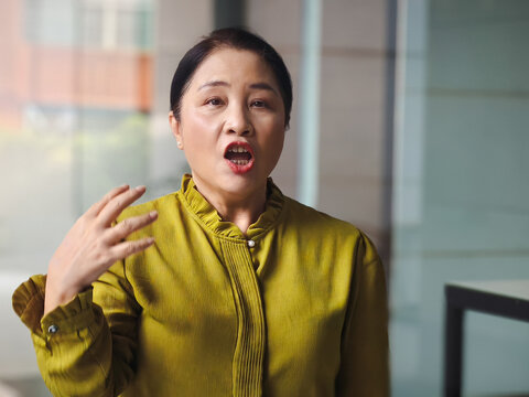 Angry unhappy upset dissatisfied middle aged asian woman with negative and hostile expression, screaming and staring at you