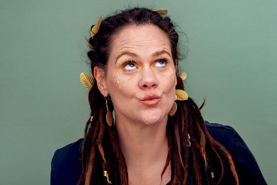 Playful Alternative Woman with Dreadlocks and Gold Makeup Looking Up