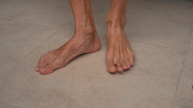 Man rubbing bare feet on tiled floor, high quality uncompressed audio recording. Soft friction and sliding sounds. Relaxed home moment, tactile sensation and everyday lifestyle concept.