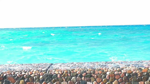 Straw beach umbrella and turquoise ocean waves. Peaceful view from under a straw beach umbrella looking out at the calm turquoise sea with gentle waves washing ashore on a beautiful sunny day.