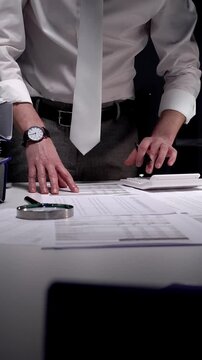 Business professional working late on financial audit in modern office, analyzing tax documents and managing paperwork deadlines with precision and expertise