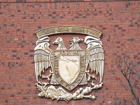 Gatineau, Quebec, Canada &ndash; March 11, 2026: A golden "UNAM coat of arms emblem", featuring a two-headed bird and a map, is mounted on a red brick wall on Prom. du Portage.