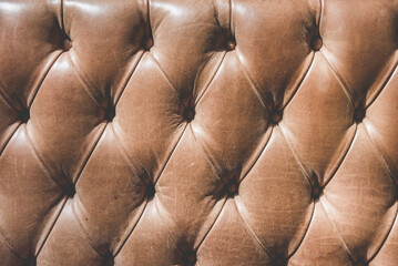 Fototapeta premium Rich brown leather Chesterfield tufted upholstery with classic geometric capitone pattern. Luxury vintage texture background perfect for premium, corporate, hospitality and interior design concepts
