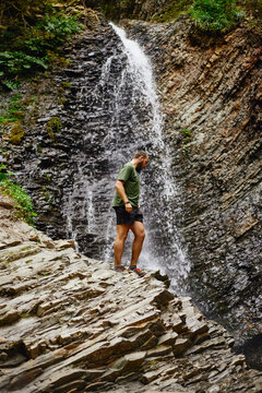 Zhenetskyi Huk Waterfall. Man stands near a waterfall and explores the rocky area. Summer Hiking in Carpathian Mountains. Ukraine