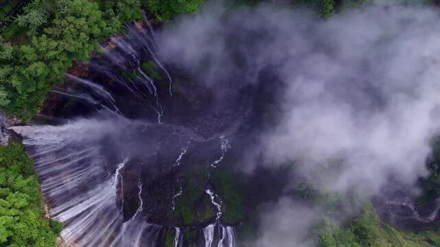 Aerial view of Tumpak Sewu Waterfall in misty landscape