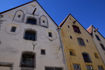Fototapeta premium Low-Angle View of Two Medieval Hanseatic Warehouse Buildings with Gothic Gabled Facades Against Blue Sky, Tallinn Old Town, Estonia