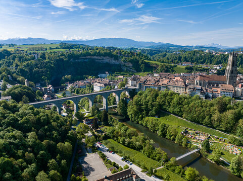 Aerial view of St-Nicolas Cathedral and the Zaehringen Bridge spanning the Sarine river valley with historic rooftops and lush green forests in Fribourg, Fribourg, Switzerland.