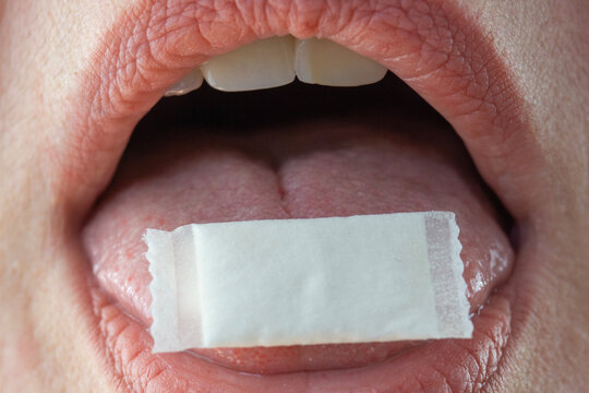 close up of mouth with white nicotine pouch on tongue concept of sublingual snus use, nicotine delivery, oral consumption, addiction habit