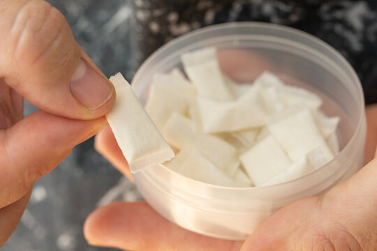 top view of open container with white nicotine pouches or snus portions in hand concept of smokeless tobacco, addiction risk, nicotine delivery habit and health danger