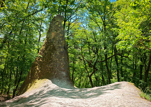 Striking rock formation named Devil's Tower rising from forest floor in B&uuml;kk Mountains, Hungary, surrounded by green woodland.