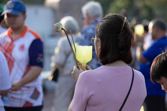Female believer walking in candlelight procession around Buddha statue on Makha Bucha Day at Phutthamonthon, close up.