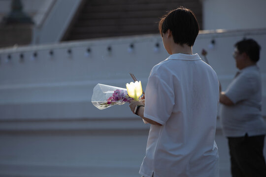 Thai woman walking in candlelight procession around Buddha statue on Makha Bucha Day, rear view, at Phutthamonthon.